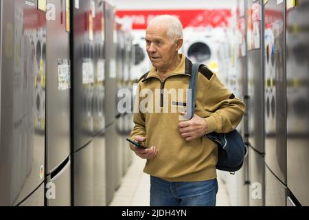senor uomo pensionato acquistare frigorifero in showroom di elettrodomestici negozio Foto Stock