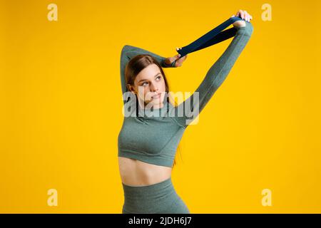 Ragazza sportiva con elastico per il fitness su sfondo giallo Foto Stock