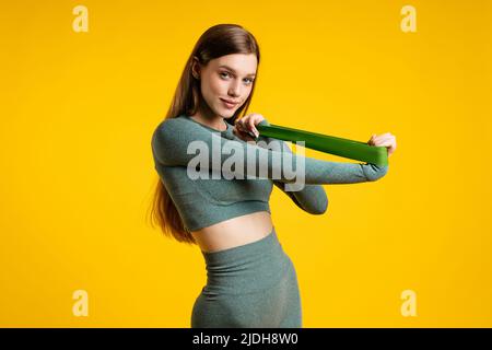 Ragazza sportiva con elastico per il fitness su sfondo giallo Foto Stock