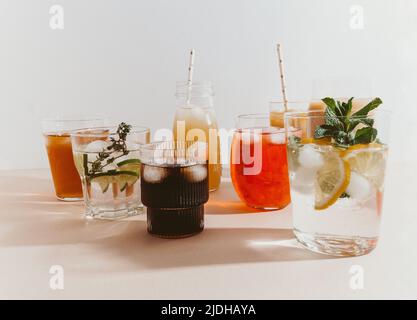 Varie bevande analcoliche rinfrescanti in bicchieri con ghiaccio. Succo di frutta diverso, limonata fatta in casa, caffè ghiacciato, tè alla frutta ghiacciata e frullati su una ba leggera Foto Stock