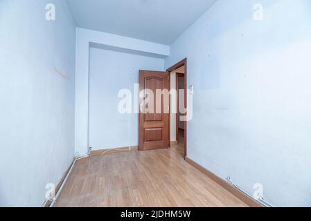 Camera vuota con parquet di quercia, pareti dipinte di blu chiaro e legno rossastro Foto Stock