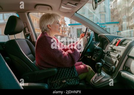 Conducente femminile con il cellulare seduto nell'auto passeggero Foto Stock