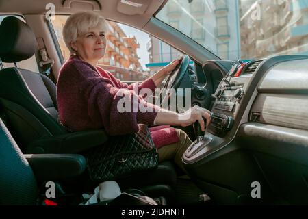 Signora dai capelli grigi seduta nella vettura del passeggero Foto Stock