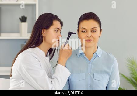 Il medico ENT utilizza l'otoscopio per esaminare l'orecchio della paziente durante l'esame medico in ospedale. Foto Stock