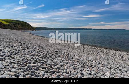 Vista panoramica sulla spiaggia di Pebble e sul mare a Greencliff Beach, con i ciottoli che si estendono lungo la costa. Incoming Tide, guardando verso Hartland Point: Foto Stock