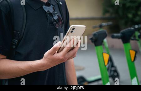 Un uomo sblocca un e-scooter con il suo cellulare. Foto Stock