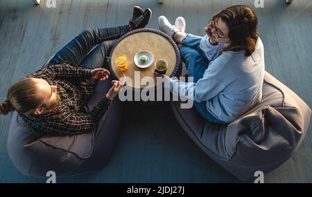 Una giovane donna e un uomo stanno parlando mentre si siedono sui sacchi di fagioli, vista dall'alto. Foto Stock