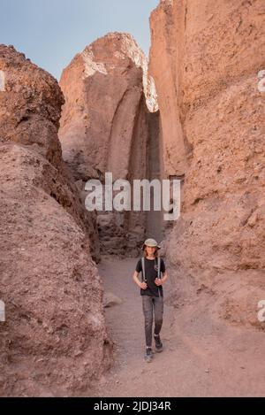 Escursionista ragazzo di fronte alla cascata asciutta scivolo al Natural Bridge Canyon, una popolare breve escursione al Death Valley National Park in California. Foto Stock