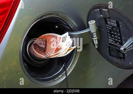 Aumento e prezzi del carburante di veicolo inaccessibili, soldi riempiti nel tappo di rifornimento dell'automobile, banconote sterling dieci libbre, prezzo per il litro per benzina & diesel Foto Stock