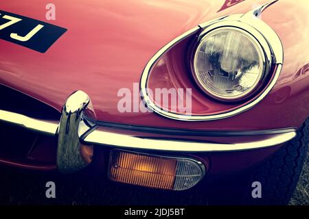 Faro anteriore in dettaglio di una classica auto a motore Jaguar e-Type rossa d'epoca dal 1970. Foto Stock