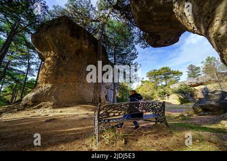 Donna seduta su una panchina nel parco della Città incantata di Cuenca, Spagna. Foto Stock