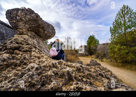 Donna seduta su una grande roccia calcarea nella Città incantata di Cuenca. Foto Stock