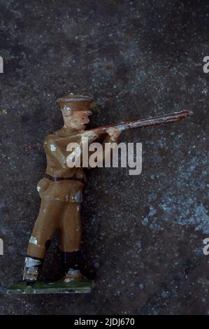 Modello di piombo indossato dell'ufficiale dell'esercito della guerra mondiale 1 che mira e spara il fucile contro il fondo metallico screziato Foto Stock