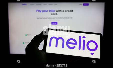 Persona che detiene il cellulare con il logo della società finanziaria statunitense Melio Payments Inc. Sullo schermo di fronte al sito web aziendale. Mettere a fuoco sul display del telefono. Foto Stock