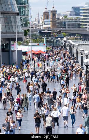 La Queen's Walk sulla riva sud del Tamigi vicino al Tower Bridge, Londra, ricca di turisti stranieri e turisti che si godono la giornata. Foto Stock
