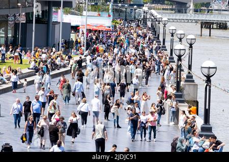 La Queen's Walk sulla riva sud del Tamigi vicino al Tower Bridge, Londra, ricca di turisti stranieri e turisti che si godono la giornata. Foto Stock