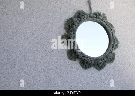 Specchio in macrama su sfondo bianco, specchio in macrama verde, decorazioni a parete, decorazioni con balcone adatte per la stagione estiva. Foto Stock