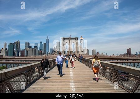 Persone sulla strada pedonale del Ponte di Brooklyn con alti edifici di Manhattan sullo sfondo a New York City, Stati Uniti d'America Foto Stock