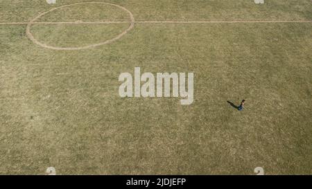 Vista con droni di un campo da calcio nel cerchio centrale, con linee distorte e erba meteorata. Foto Stock