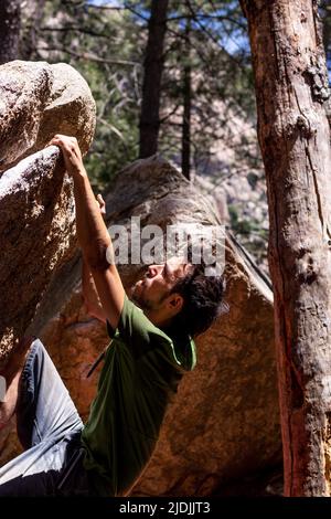 Uomo europeo in t-shirt e pantaloncini che fanno arrampicata bouldering Foto Stock