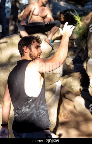 Uomo europeo in t-shirt e pantaloncini che fanno arrampicata bouldering Foto Stock