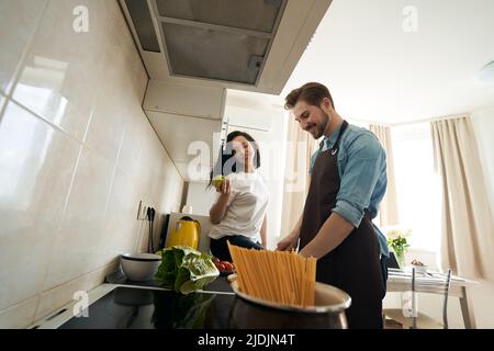 Donna che osserva l'uomo che prepara la cena per lei Foto Stock