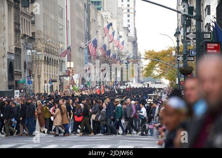 Manhattan, New York, USA - Novembre 11. 2019: Persone che attraversano Fifth Avenue a NYC durante la Veterans Day Parade. Membri delle forze armate in background Foto Stock