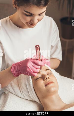 Primo piano ritratto di estetista che fa l'idrata trattamento di microdermoabrasione facciale nel salone di spa. Donna al centro estetico di bellezza slinico. Vuoto Hydra Foto Stock