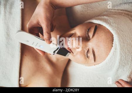 Giovane donna che ottiene la pelle di buccia ultrasonica alla clinica di cosmetologia. Cosmetologia estetica, cura del viso. Cura della pelle. Foto Stock