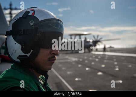 220617-N-DW158-1245 MAR DELLE FILIPPINE (17 giugno 2022) il Lt. Ivan Nguyen, di San Diego, guarda un e-2D Hawkeye attaccato alle Tigertails of Airborne Early Warning Squadron (VAW) 125, si prepara al lancio dal ponte di volo dell'unica compagnia aerea statunitense USS Ronald Reagan (CVN 76). Ronald Reagan ha ospitato cinque Midshipmen della U.S. Naval Academy per la loro crociera estiva, consentendo loro di sperimentare la vita quotidiana a bordo di un vettore aereo. Ronald Reagan, l'ammiraglia del Carrier Strike Group 5, fornisce una forza pronta per i combattimenti che protegge e difende gli Stati Uniti, e sostiene Foto Stock