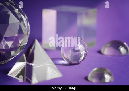 Luce rifrangente a prisma di cristallo, cristalli magici e piramide, sfera e cubo su sfondo viola. Pratica di cristallo di guarigione spirituale. Feng Shui, bravo Foto Stock