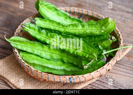 Fagiolo alato su fondo basket e sacco, Psofocarpus tetragonolobus - fagiolo alare verde o fagiolo a quattro angoli Foto Stock