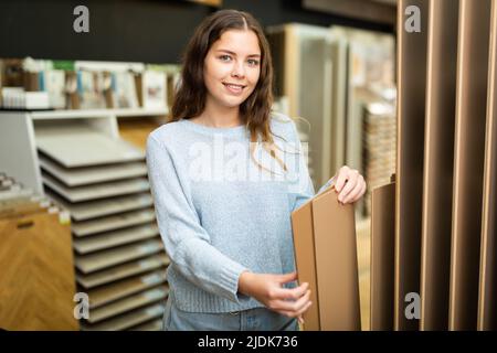 Cliente femmina che tiene campioni di pannelli di legno nel negozio di ferramenta Foto Stock