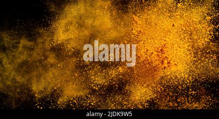 Esplosione, schizzi di curcuma su sfondo nero. India Seasoning. La polvere arancione della radice curmerica. Foto Stock