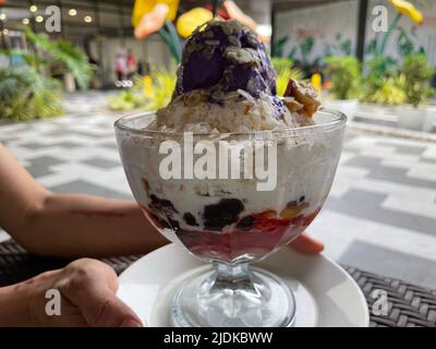 Filippine. 18th giugno 2022. Halo-Halo è un dolce filippino popolare della nazione isolana e un drink allo stesso tempo. Per prepararlo, i frutti zuccherati come le banane o le strisce di cocco, il mung candito o i fagioli del rene e i pezzi di gelatina rossi e verdi sono coperti con ghiaccio raschiato. Il tutto è ricoperto di latte condensato e ricoperto di leche flan (la versione filippina del crema caramello) o di gelato al gusto di giallo viola e cosparso di riso giovane tostato. (A dpa 'Halo-Halo, Gazoz e Pea di farfalle: Bevande estive in tutto il mondo') Credit: Girlie Linao/dpa/Alamy Live News Foto Stock