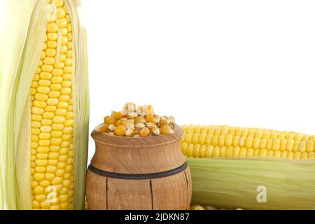 Barile di legno con chicchi di mais granaglie vicino a mais fresco o mais sulla pannocchia con foglie su un fondo bianco in un concetto di agricoltura e raccolto, s Foto Stock