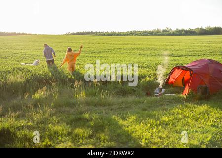 Le giovani coppie giocano con il loro cane al campeggio Foto Stock