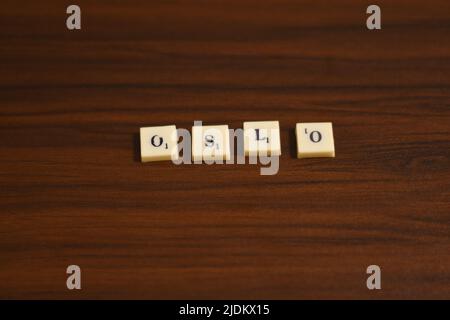 Primo piano mirato selettivo della parola Oslo. Fatto usando le lettere in blocchi in uno sfondo di legno. Foto Stock