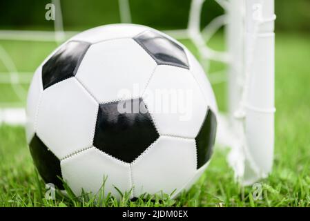 Palla bianca e nera generica (calcio) accanto al mini goal Foto Stock