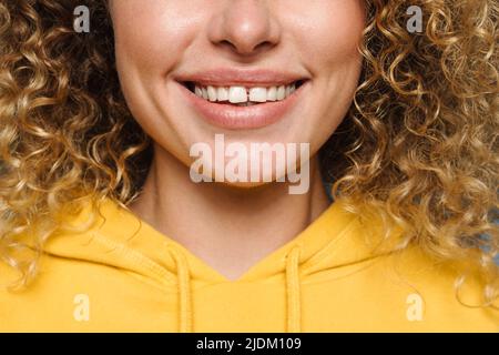 Giovane donna bionda vestita con felpa con cappuccio sorridente a fotocamera isolata su sfondo blu Foto Stock