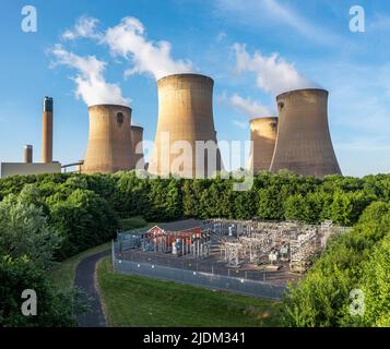 Una vista aerea delle torri di raffreddamento e del camino di una grande centrale elettrica a carbone che genera elettricità con apparecchiature elettriche per alimentare energia Foto Stock