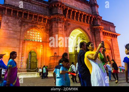 Mumbai, Maharashtra, India : la gente posa per selfie al crepuscolo di fronte al cancello illuminato dell'arco monumentale dell'India costruito tra 1913 e 1924 i Foto Stock