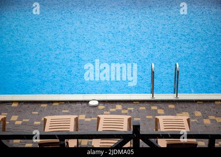 La pioggia incredibilmente pesante e il vento veloce e duro rovinano il caldo e soleggiato clima estivo nella base tranquilla con piscina per una vacanza attesa a lungo Foto Stock