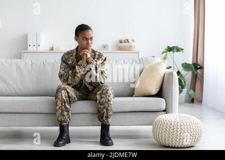 Donna soldato nero pensivo in uniforme militare con ptsd seduta sul divano Foto Stock