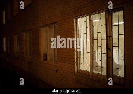 Finestra in edificio di sera. Calandra sul finestrino di notte. Dettagli dell'edificio. Foto Stock