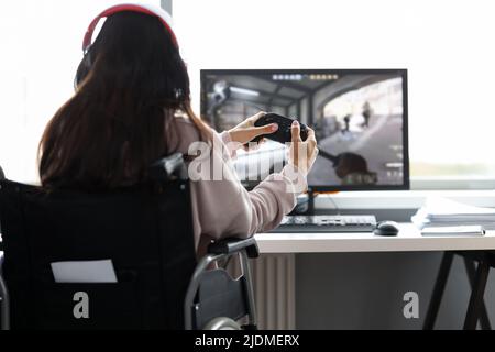 Donna in sedia a rotelle che si diverte a giocare ai giochi per computer Foto Stock