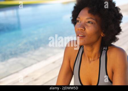 Giovane afroamericana che guarda via mentre si esercita a bordo piscina Foto Stock