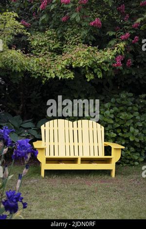 Una graziosa panca adirondack colorata in un giardino. Foto Stock