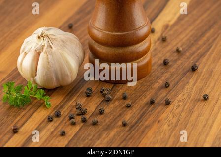 Il tritatutto per pepe con aglio e spezie sul tavolo delle noci in primo piano Foto Stock