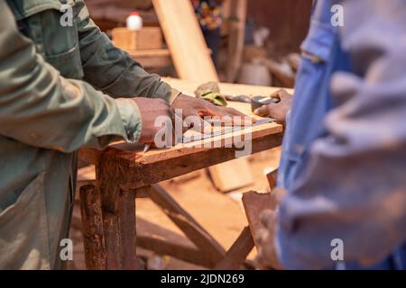 Primo piano delle mani di due carpentieri che effettuano le misurazioni su un asse di legno durante il lavoro Foto Stock